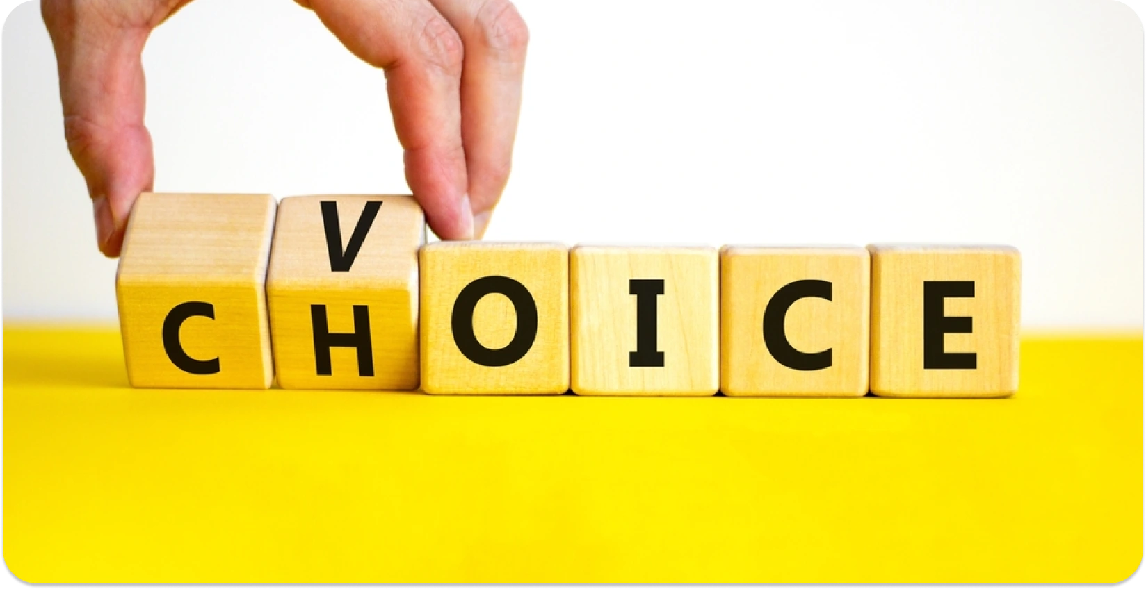 Hand adjusting wooden blocks to spell the word "CHOICE" on a yellow background.