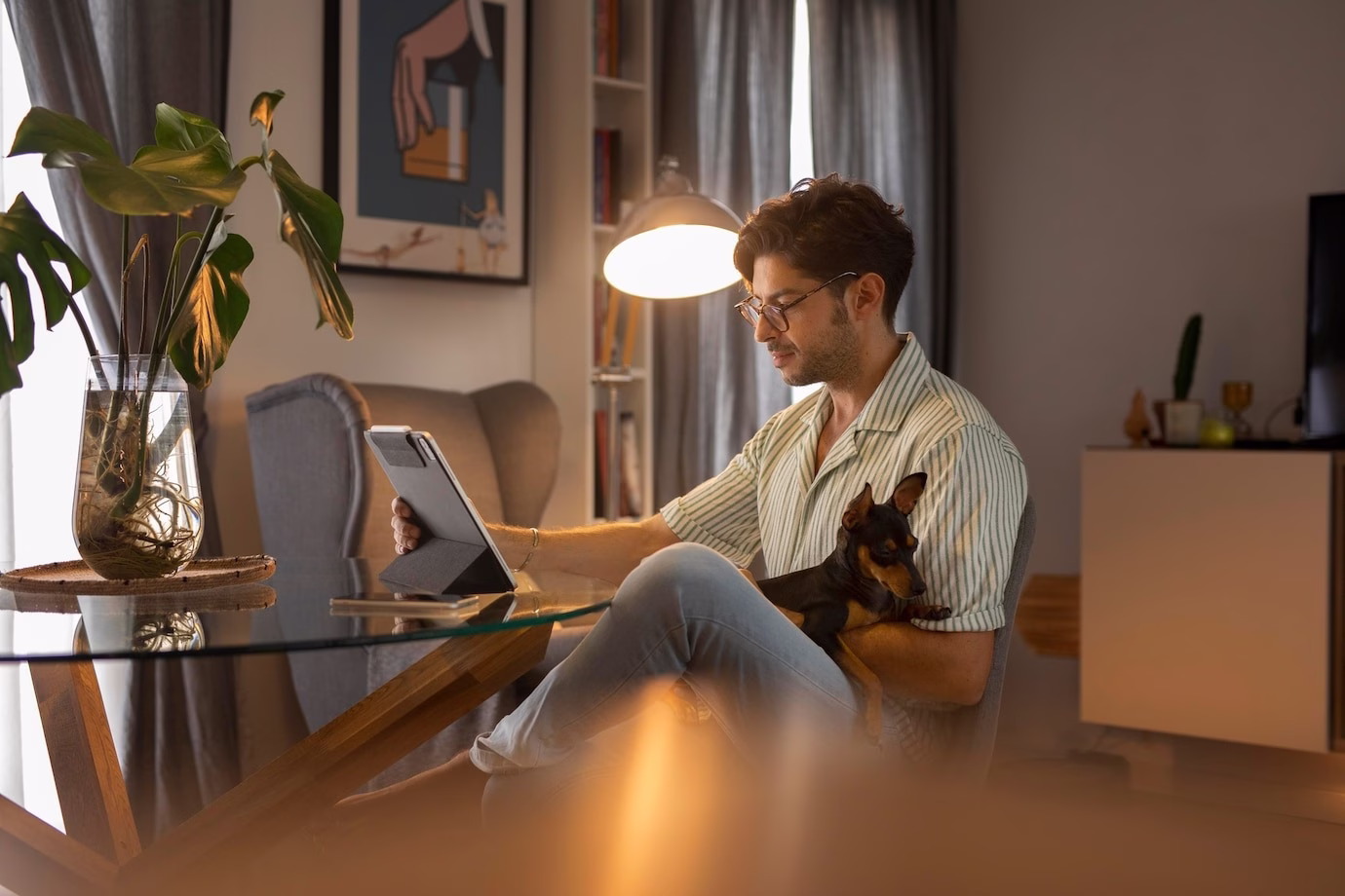 Man working on tablet while relaxing at home with dog in comfortable living room