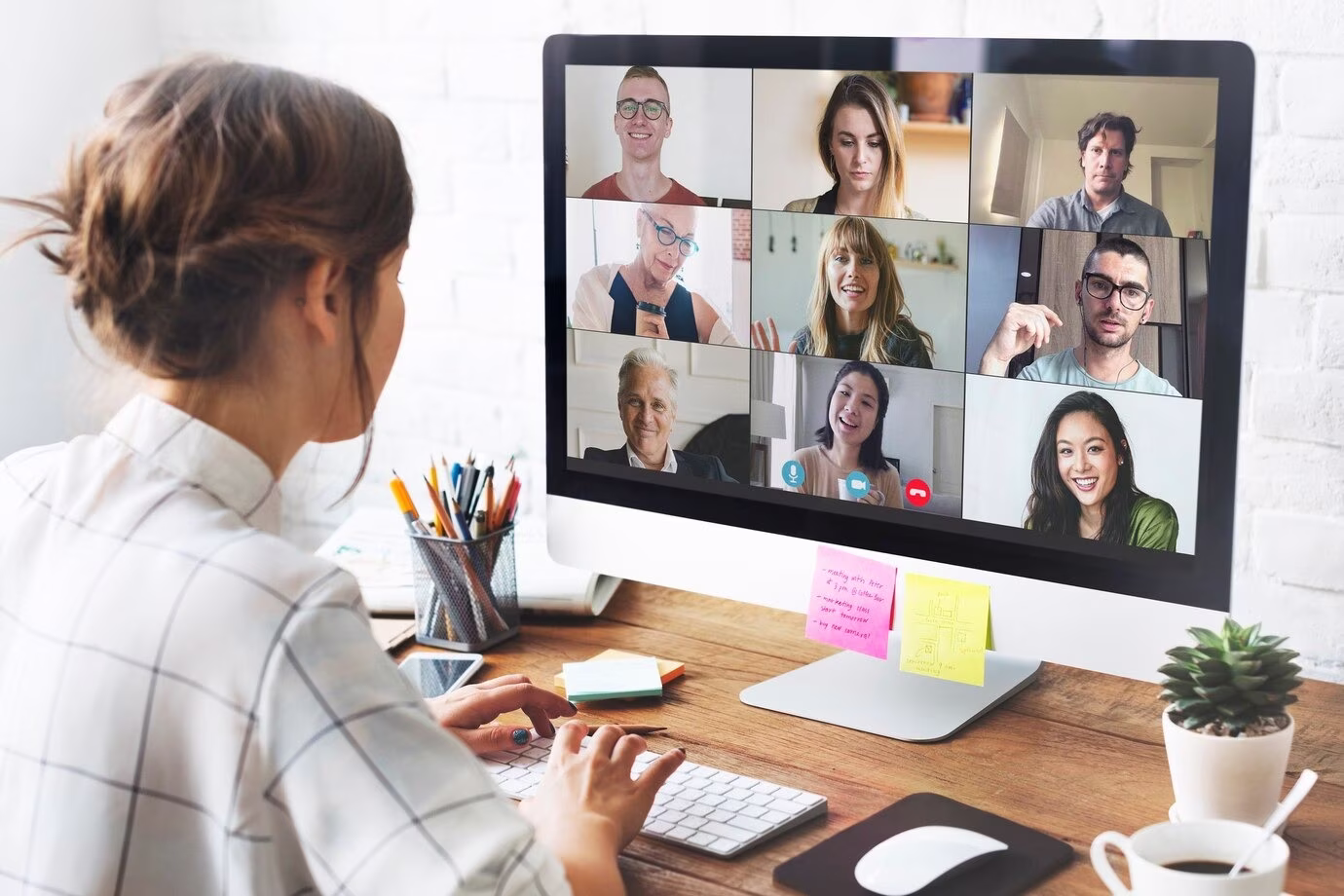 Person attending video conference with multiple participants displayed in grid layout on screen