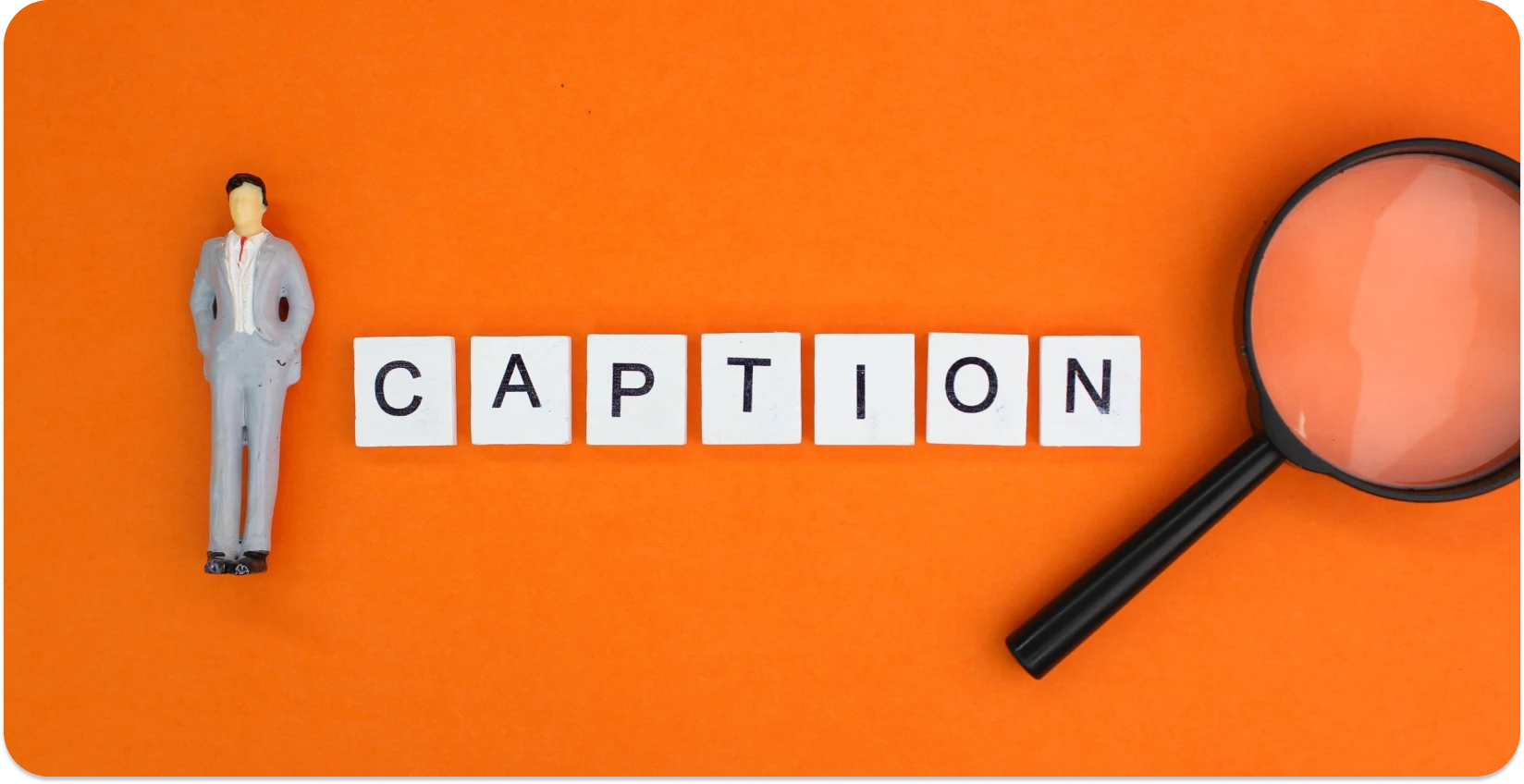 'CAPTION' 블록과 돋보기가 있는 미니어처 피규어는 캡션 디테일에 중점을 둔 것을 상징합니다.