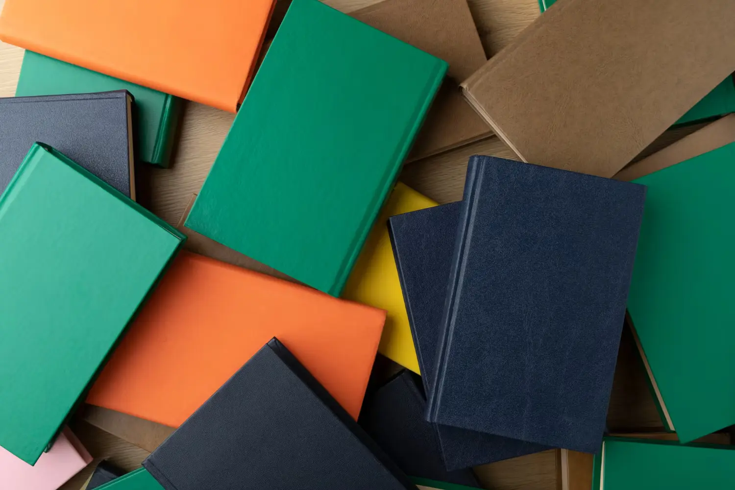 Assorted colorful books stacked and scattered on a wooden table.