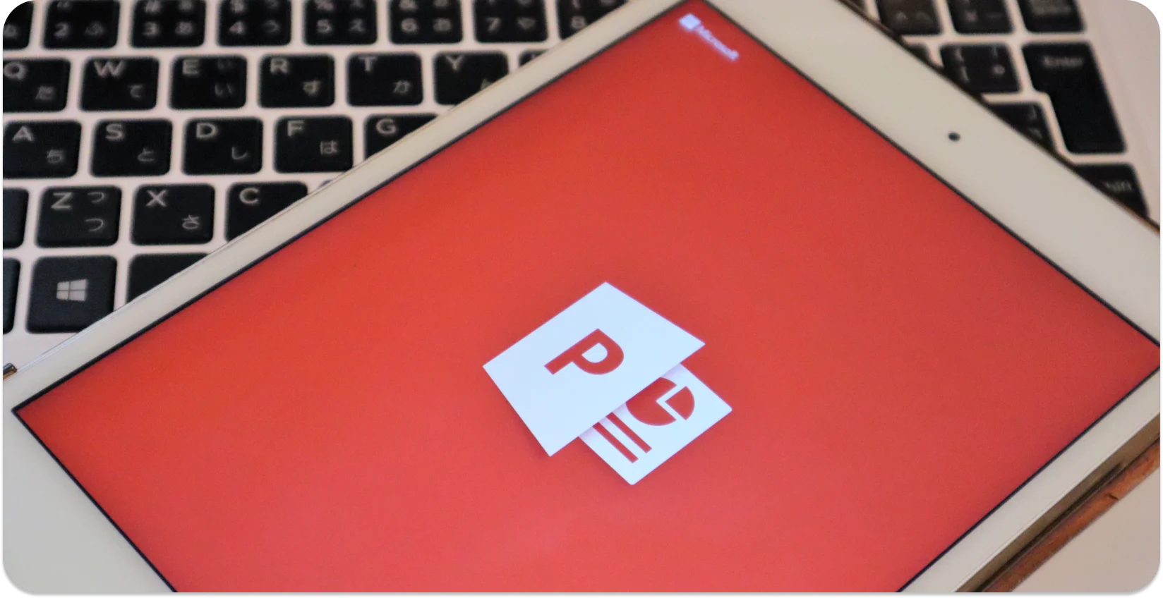 Tablet su una tastiera che visualizza il logo di PowerPoint, pronto per la conversione da audio a testo.