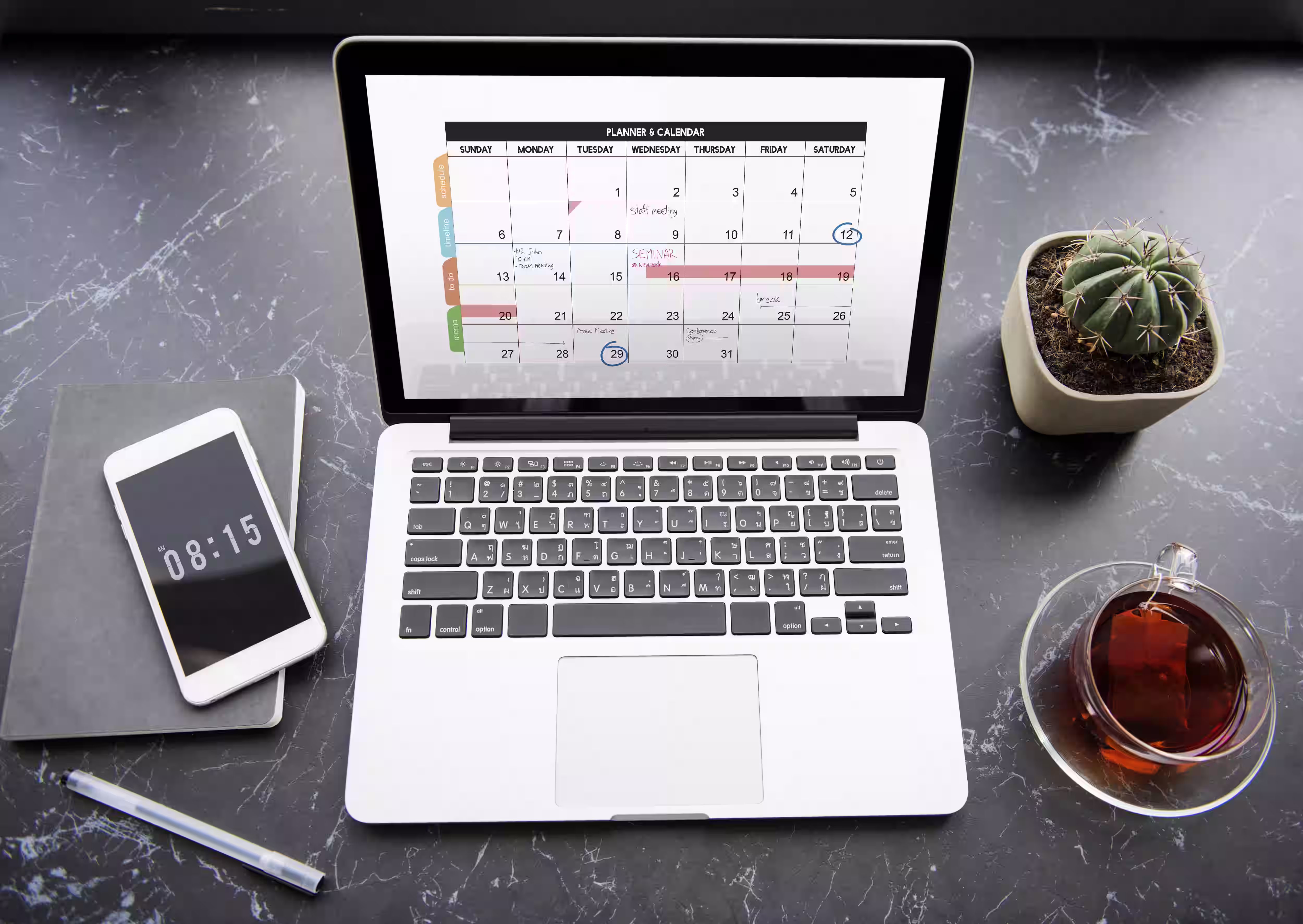 Laptop displaying a monthly calendar with color-coded events alongside smartphone on desk